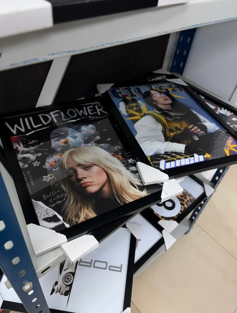 Framed posters with protective corners waiting on a studio shelf