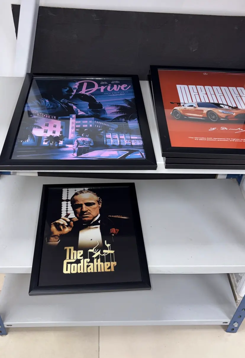 Framed Drive, Mercedes and The Godfather posters on studio shelving